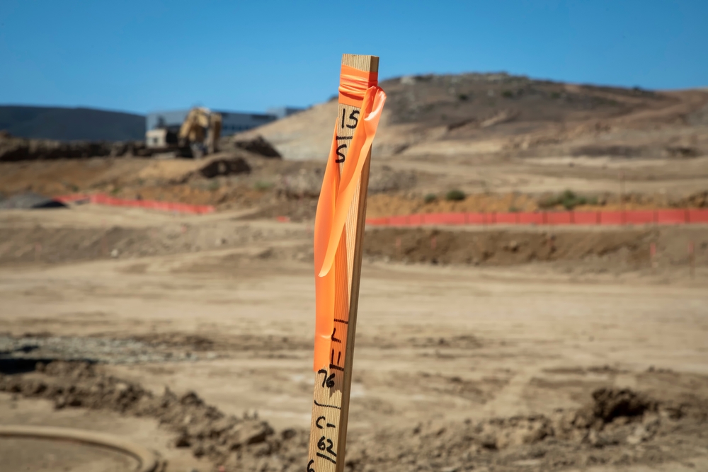 Construction,Grading,Stake,With,Construction,Equipment,In,Background