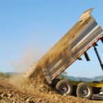 Dump,Truck,Dumping,Rock,And,Dirt,In,The,Prep,For