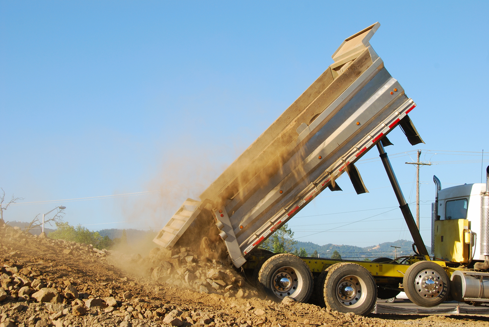Dump,Truck,Dumping,Rock,And,Dirt,In,The,Prep,For